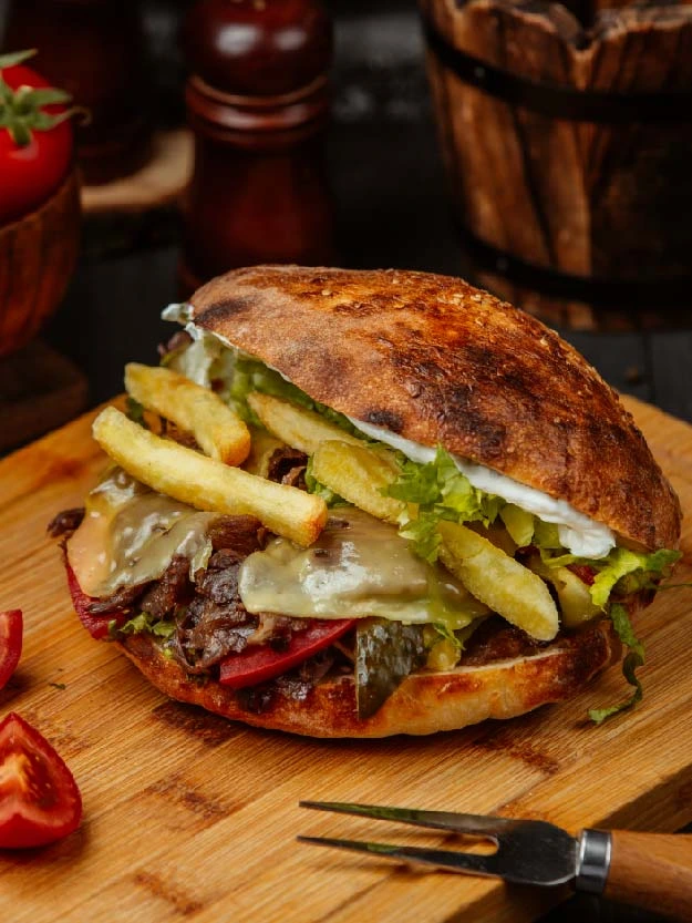 a burger with fries and cheese on a wooden board